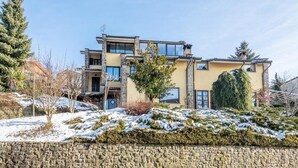 A modern two-story house with a stone facade, large windows, and a snow-covered landscape. - Holiday Apartment "Nigella Langhe Home" with Mountain View, Balcony & Wi-Fi (Niella Belbo)