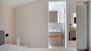 A modern hotel room with a bed, a bathroom with a mirror, and a shower curtain. - Holiday Apartment "Nigella Langhe Home" with Mountain View, Balcony & Wi-Fi (Niella Belbo)