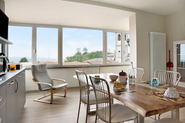 A dining area with a wooden table, metal chairs, and a view of a building through large windows.