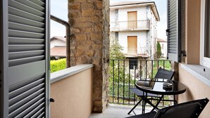 A balcony with a table and chairs, a stone pillar, and a view of a building with balconies. - Holiday Apartment "Nigella Langhe Home" with Mountain View, Balcony & Wi-Fi (Niella Belbo)
