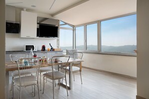Una cocina moderna con armarios blancos, un televisor de pantalla plana y un comedor con sillas de metal y una mesa de madera.