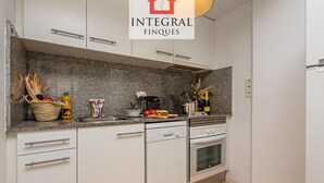 Una cocina moderna con armarios blancos, encimeras de granito, lavavajillas y horno.