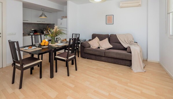 Una sala moderna con comedor, sofá y cocina al fondo.