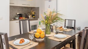 Una cocina moderna con una mesa de comedor lista para dos personas, con un florero con flores y una cesta de naranjas.