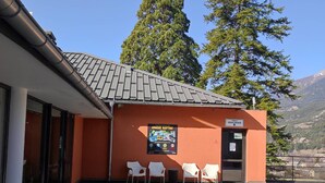 A building with a tiled roof, a sign reading "APACHE RACING," and a view of mountains in the background. - Duplex T3 in Jausiers - 6 people, terrace, parking (Jausiers)