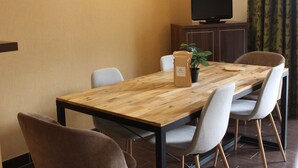 A dining area with a wooden table, four chairs, a potted plant, a television on a cabinet, and a wall with a light fixture. - Duplex T3 in Jausiers - 6 people, terrace, parking (Jausiers)