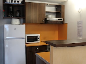 A compact kitchen with a refrigerator, microwave, and a coffee maker on the countertop.