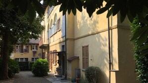 A narrow alleyway with a building featuring a stone pathway, a small garden, and a door with a potted plant. - Apartment 'In Villa Belli' with Shared Garden & Wi-Fi (Miasino)