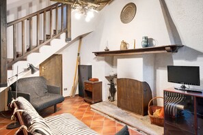 Une pièce avec un escalier, un canapé, une télévision et une cheminée.