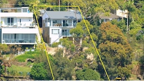 Une propriété située en bord de mer, comprenant une maison moderne à deux étages, un balcon et une vue sur la plage.
