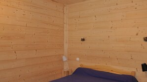 A wooden-paneled room with a single bed, a nightstand, and a lamp. - Charming apartment with terrace, covered parking and WIFI (La Chapelle-d'Abondance)