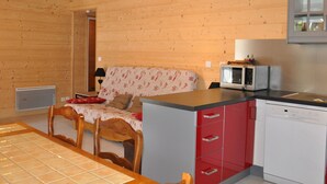 A wooden interior with a dining area, a sofa, a television, and a dishwasher. - Charming apartment with terrace, covered parking and WIFI (La Chapelle-d'Abondance)