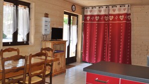 A wooden interior with a dining table, chairs, a TV, and a red kitchen counter. - Charming apartment with terrace, covered parking and WIFI (La Chapelle-d'Abondance)
