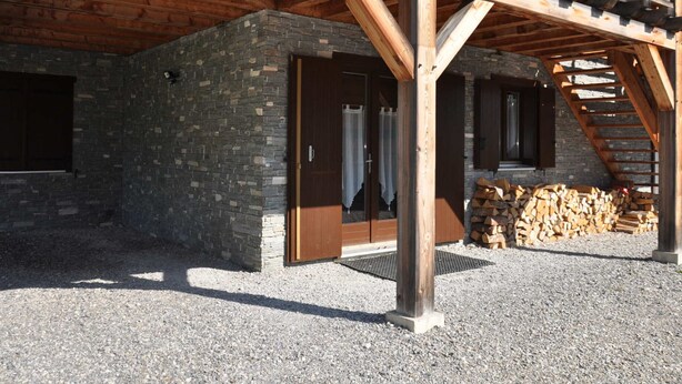 A building with a stone exterior, wooden beams, a door, and a staircase. - Charming apartment with terrace, covered parking and WIFI (La Chapelle-d'Abondance)