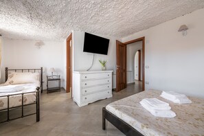 A bedroom with a bed, a dresser, a television, and a lamp.