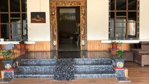 Un edificio de madera tradicional con un acceso decorativo, una escalera de piedra y plantas en macetas.