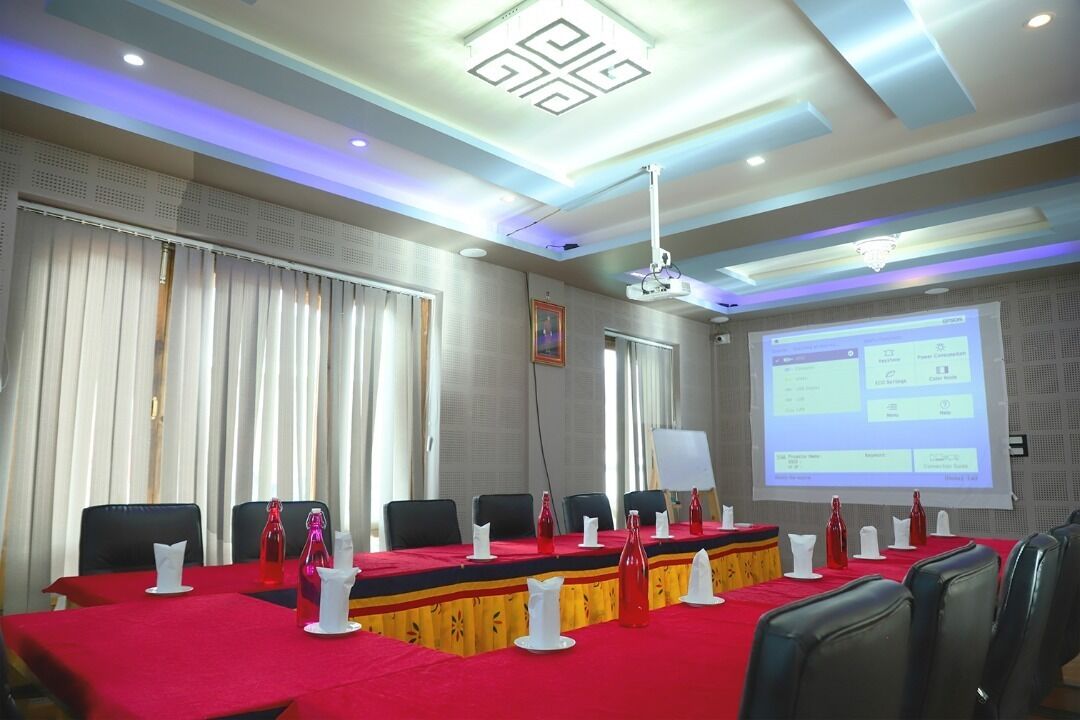 Una sala de conferencias con una larga mesa, sillas y una pantalla de proyector mostrando una presentación.