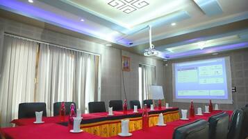 Una sala de conferencias con una larga mesa, sillas y una pantalla de proyector mostrando una presentación.
