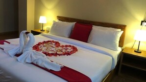 Una cama bien hecha con un arreglo floral en forma de corazón y dos toallas dobladas en forma de cisnes.