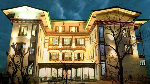 Un edificio grande de varios pisos con fachada simétrica, múltiples ventanas y una entrada central con porche.