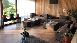 Un salón acogedor con techo de madera, un amplio sofá, una mesa de centro y plantas en macetas.