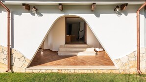 Une maison avec une façade en pierre, un hall d’entrée carrelé et un escalier apparent qui mène à l’intérieur.