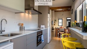 A modern kitchen with a built-in oven, a dishwasher, and a sink. There is a dining area with yellow chairs and a table. - Beachfront Fisherman's Cottage with AC, Wi-Fi & Parking (Palamós)