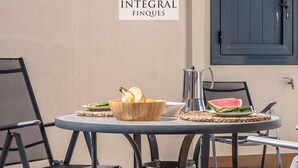 A round table with chairs, a bowl of fruit, a metal pitcher, and a plate with a slice of watermelon. - Beachfront Fisherman's Cottage with AC, Wi-Fi & Parking (Palamós)