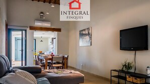 A living room with a sofa, a TV, and a dining area in the background. - Beachfront Fisherman's Cottage with AC, Wi-Fi & Parking (Palamós)