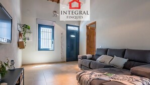 A living room with a sofa, a TV, and a door. - Beachfront Fisherman's Cottage with AC, Wi-Fi & Parking (Palamós)