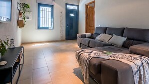 Una sala de estar con un sofá, un televisor y una puerta.