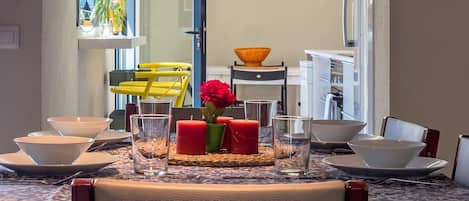 A dining area with a table set for four, including bowls, glasses, and a vase with flowers.