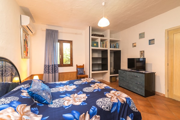 A bedroom with a bed, a TV, a wardrobe, and a bookshelf.