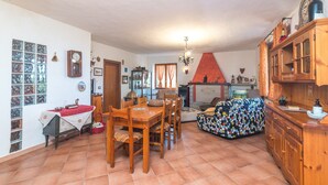 Una zona pranzo con tavolo e sedie in legno, un divano decorato e un pavimento piastrellato.