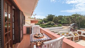 En balkon med et spisebord, en stol og grillområde.