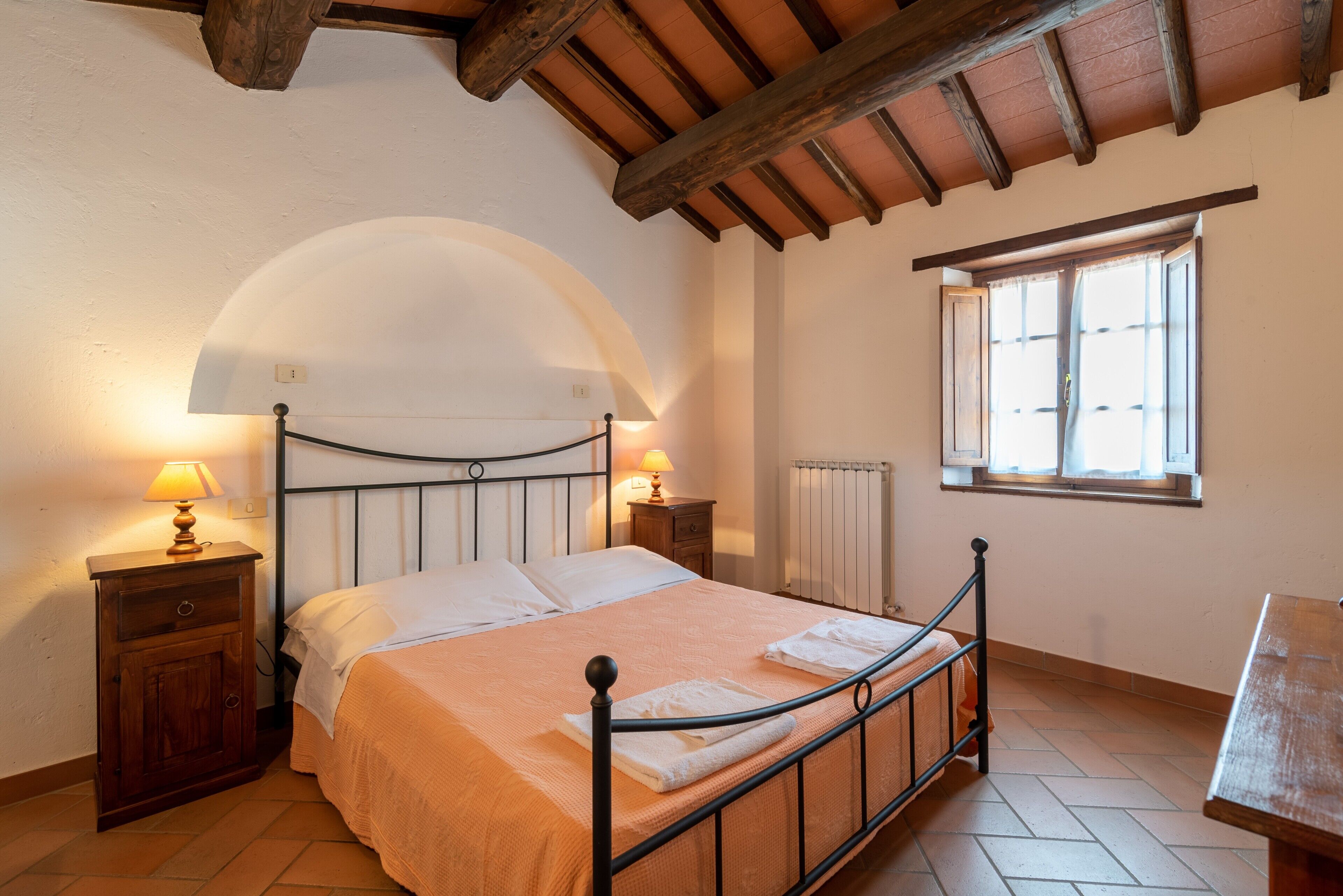 Una camera da letto con un letto, comodini, una finestra e un soffitto in legno.