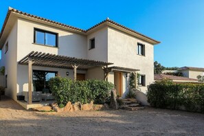 Une maison à deux étages avec un patio, une pergola et une allée gravillonnée.