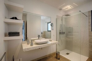 Une salle de bain moderne avec deux lavabos, un grand miroir et une douche à parois de verre.