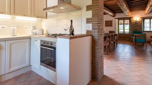 A kitchen with white cabinets, a stove, and a brick column.