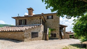 A stone building with a tiled roof, a staircase, and a small garden area.