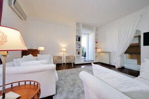 A hotel room with a bed, two armchairs, a small table, a lamp, a bookshelf, and a view of the outside. - San Giovanni - Apartment for 4 pax with beautiful terrace close to the Coloseum (Roma)