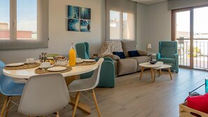 Un soggiorno moderno con zona pranzo, che include un divano, poltrone, un tavolino da caffè e opere d'arte alle pareti.