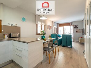 A modern kitchen with a toaster, a sink, and a dining area with teal chairs and a table. - Modern Apartment, 2 Bedrooms, 150m from Beach, Central Palamós, with Parking, WiFi & A/C (Palamós)