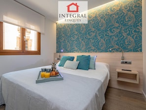 A hotel room with a bed, a tray with breakfast, a patterned wall, and a window.