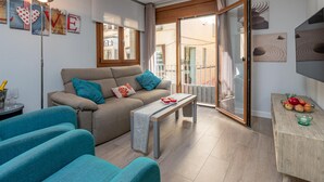 A living room with a sofa, a coffee table, and a dining area with a table and chairs. - Modern Apartment, 2 Bedrooms, 150m from Beach, Central Palamós, with Parking, WiFi & A/C (Palamós)