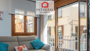 A modern living room with a sofa, cushions, a coffee table, and a balcony with a view of the city. - Modern Apartment, 2 Bedrooms, 150m from Beach, Central Palamós, with Parking, WiFi & A/C (Palamós)