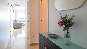 Un pasillo con un aparador de vidrio, un jarrón con flores y un espejo en la pared.