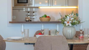 Un comedor moderno con una mesa de madera dispuesta para dos personas, un florero y un frutero en la encimera.