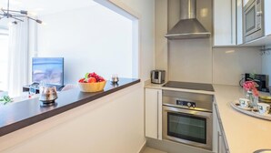 Una cocina moderna con un ventanal grande, un cuenco de fruta, un tostador y un microondas.