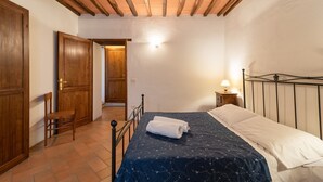 A bedroom with a bed, wooden door, and a chair. - Agriturismo 'Cuiano La Loggetta' with Shared Pool, Garden and Wi-Fi (Cortona)